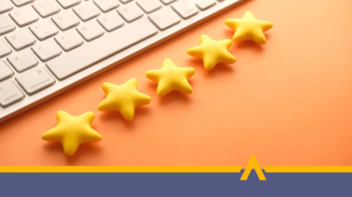 Pięć żółtych gwiazdek ułożonych w rzędzie obok klawiatury na pomarańczowym tle, symbolizujących wysoką ocenę lub pozytywne opinie